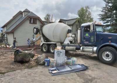 Concrete being poured at a residential construction site, with workers carefully guiding the process.